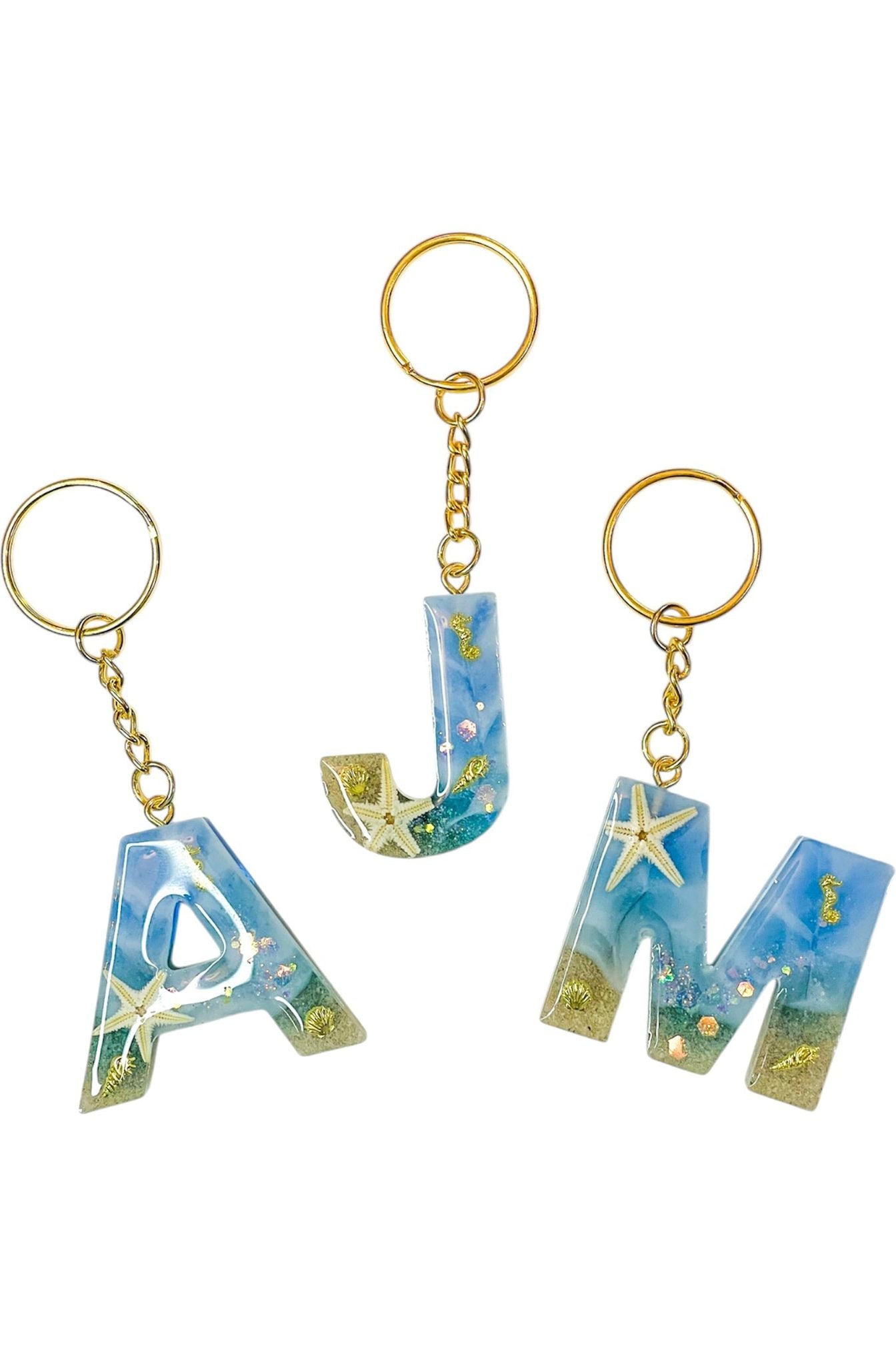 Beach-themed resin letter keychain with sand and shells